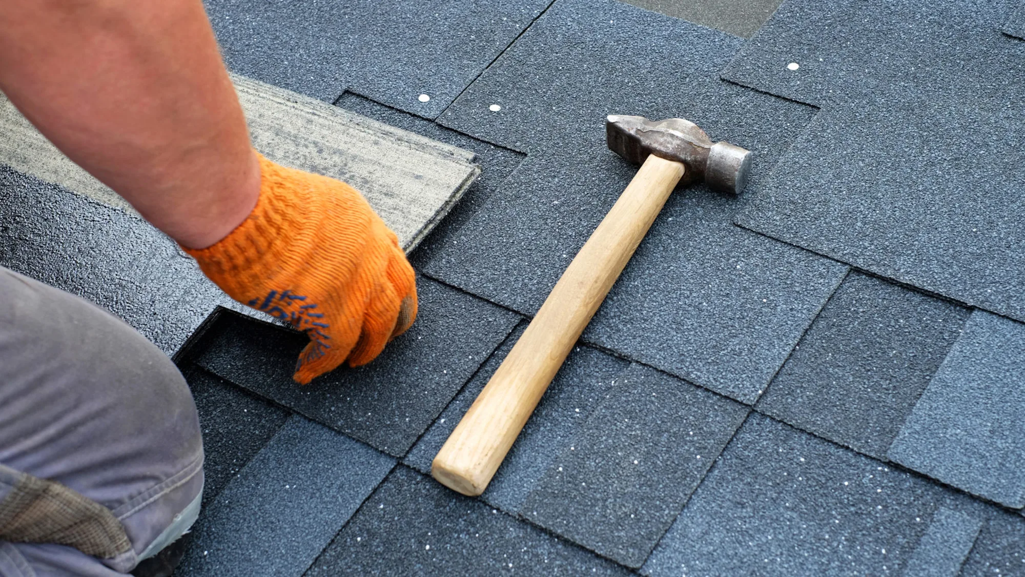 Roofer hammering a shingle into place
